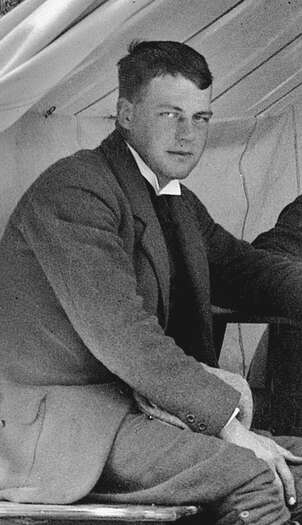 Bildet viser en ung Anton W. Brøgger sittende i et telt. Han ser rett inn i kamera.