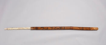 (UEM44011)&amp;#160;Staff with delicate engravings of human- and animal-like figures. The staff, which is most likely only a part of a larger ceremonial staff or artefact, is made with all seven image slots. The intricate engravings show scenes from village life. The decorative engravings on the staff were probably designed to represent the breadth of a leader’s responsibility and concern. The engravings are representations of life itself. Material: Bone, wood, and bamboo Region: Bas-Congo, Bakongo Length: 94,5 cm, diameter: 4 cm. Arrival: Donated to the Museum by Randi Schrader Nielsen, 1969. Initially in the possession of Fredrik August Michelet (1856-1916).