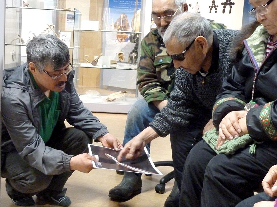Jacob Keanik (interpreter) and Elders Christian Nalungiaq, Dominiqe Inutuinaq and Theresa Sikkuark studying photographs of objects from Amundsen’s Gjoa Haven collection at the Nattilik Heritage Centre, Gjoa Haven, April 2015