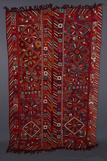 UEM49204. Both panels have double vertical borders with the characteristic multi cloured diagonal lines pattern on all four edges. The motifs are all bold. In the centre of both panels there is a small diamond with two bigger diamonds on either side. In the middle of these is a big flower with ray like petals.Other motifs consist of pecking birds, human figures (girls with blue or red hair in a row, and dancing girls), flowers and geometrical patterns.  