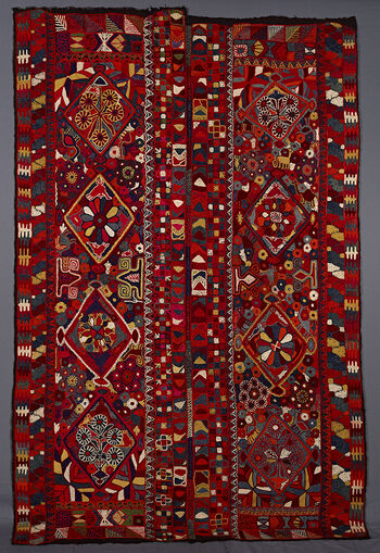 UEM49210. The blanket has double borders at vertical edges but no characteristic multi coloured diagonal-lines pattern. In the centre of the panels there are four diamonds within which there are flowers and animals surrounding the diamonds a profusion of flowers and animals such as camels and dogs, also insects and other stylised unidentifiable motifs. 
