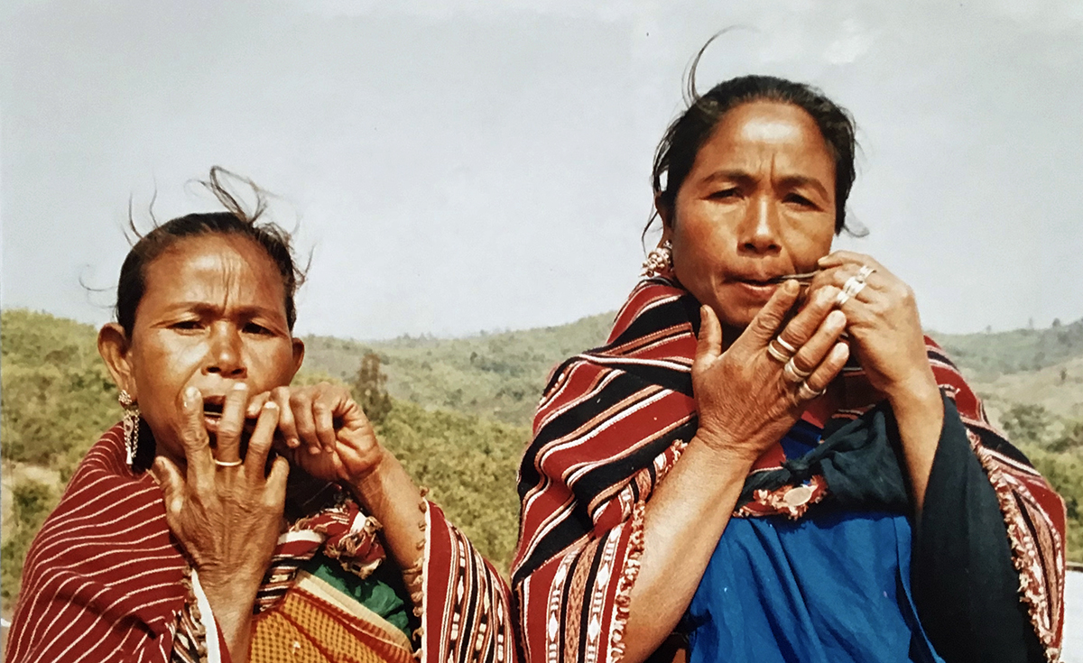 Two women playing harp made from baboo.