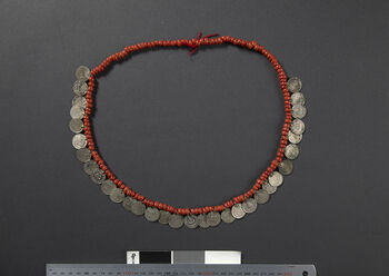 (UEM46904) Glass or ceramic beads and coins strung on a cotton cord. This is a widely used piece of jewelry worn for celebrations and rituals. In 1993, when Kaban Rongpharpi from Dokmoka made this necklace, this type of jewelry was not available pre-made on the market. She collected coins, went to the blacksmith to have loops soldered onto them, bought beads, and strung everything together on a cotton cord.