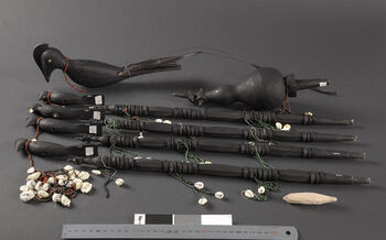 (UEM46968) Used in the death ritual Chomankan . Towards the end of the ritual, the youth from the surrounding villages arrive. The unmarried boys are gathered in their village’s Risomar . The leader, Klengsarpo , comes forward carrying the Jambeli Athon , while the deputy leader, Klengdun , carries the Sirko (see UEM46967 ). The boys and girls then dance around the Jambeli Athon and sing erotic songs to awaken the life forces once again. Made by Lota Sing Rongpi, village Phangcho. Material: Wood, cowrie shells and beads. West Karbi Anglong, Hamren district. In this photograph, the totem is stripped down.