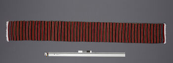 (UEM46889) Floor loom, weft faced weave. For women. When a respected person is welcomed into a house or being honoured, a scarf, poho, is draped around the neck of the person. As white and red ones are reserved for men only, the striped ones are reserved for women. This is a recent ‘invention’ that shows the same respect to women as to men. The model is an example of the striped shawls, pesarpi , used by women. Muffler/ poho . Weft faced weave. Serdihun Weaving Co-operative Society, Hidipi. Material: Acryl.