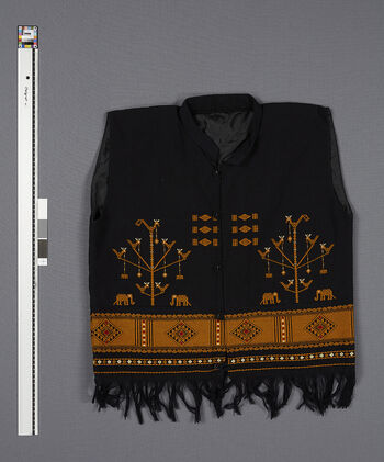 (UEM46897) Floor loom, plain weave with pick-up pattern. This waistcoat is an innovation, an attempt to make something “modern” based on traditional techniques and design. This model was very popular in the 1990's, especially among the well-educated men in the administrative centres. It can be used together with shirts and trousers. The motif is Jambili-Athon , the totem had never been used as a motif in a woven textile before. The totem which is in use during the Chomankan death ritual has become a symbol of identity for the Karbi people. Material: Acryl . Diphu district.