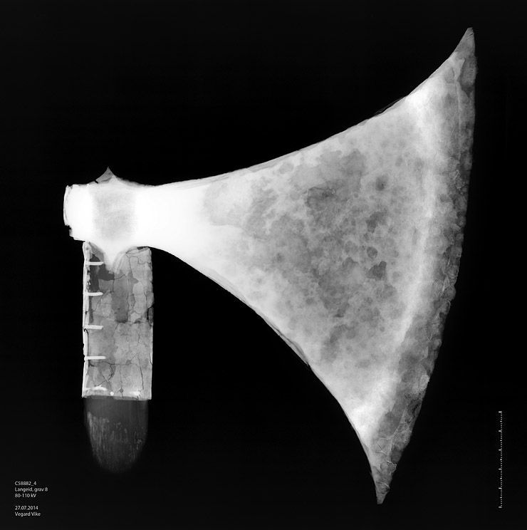 X-ray of the axe. Two X-ray photographs juxtaposed. You can see the thickening of the blade behind the cutting-edge and weld line at the insertion of the steel bit. You can also see the pins fastening the brass banding of the haft.