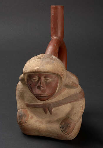 (UEM9972) Bottle in form of a kneeling man dressed in a white tunic and headdress. He wears a sling on his back, tied on the chest, facial painting on cheek and nose. The man´s nose is damaged by a disease (Leishmaniasis). Mold made. Polychrome painting reddish brown (face, stirrup-spout)), brown (sling), white (clothes, nails). The hands, with exception of the nails, are not covered with paint. Moche, 100–800, Peru.