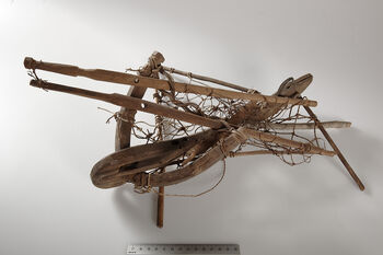 (UEM12186)&amp;#160;Rev. Bodding’s notes: 'The catch is carried out in the following way: The trap is covered with fresh leaves and placed on the pole. Underneath the trap a cage is located in which there is a lure (said always to be a male). In addition, another dove is placed on the crocked stick on the back end of the trap; here it is tied with the skin drawn over its eyes and fastened with the help of a thorn or similar, so that it cannot see. When the trapper comes to a place where he thinks there may be doves he rams the pole into the ground, arranges the trap and hides nearby. By the cooing of the lure other doves (said to be males) come to fight and to pose for the blinded dove. They sit on the sticks inside the trap and the lid closes down on them. The catch goes fast when one has a good lure.' Material: Wood, leather (skin), bamboo, vegetable fibre. Length: 38 cm, width: 30 cm.
