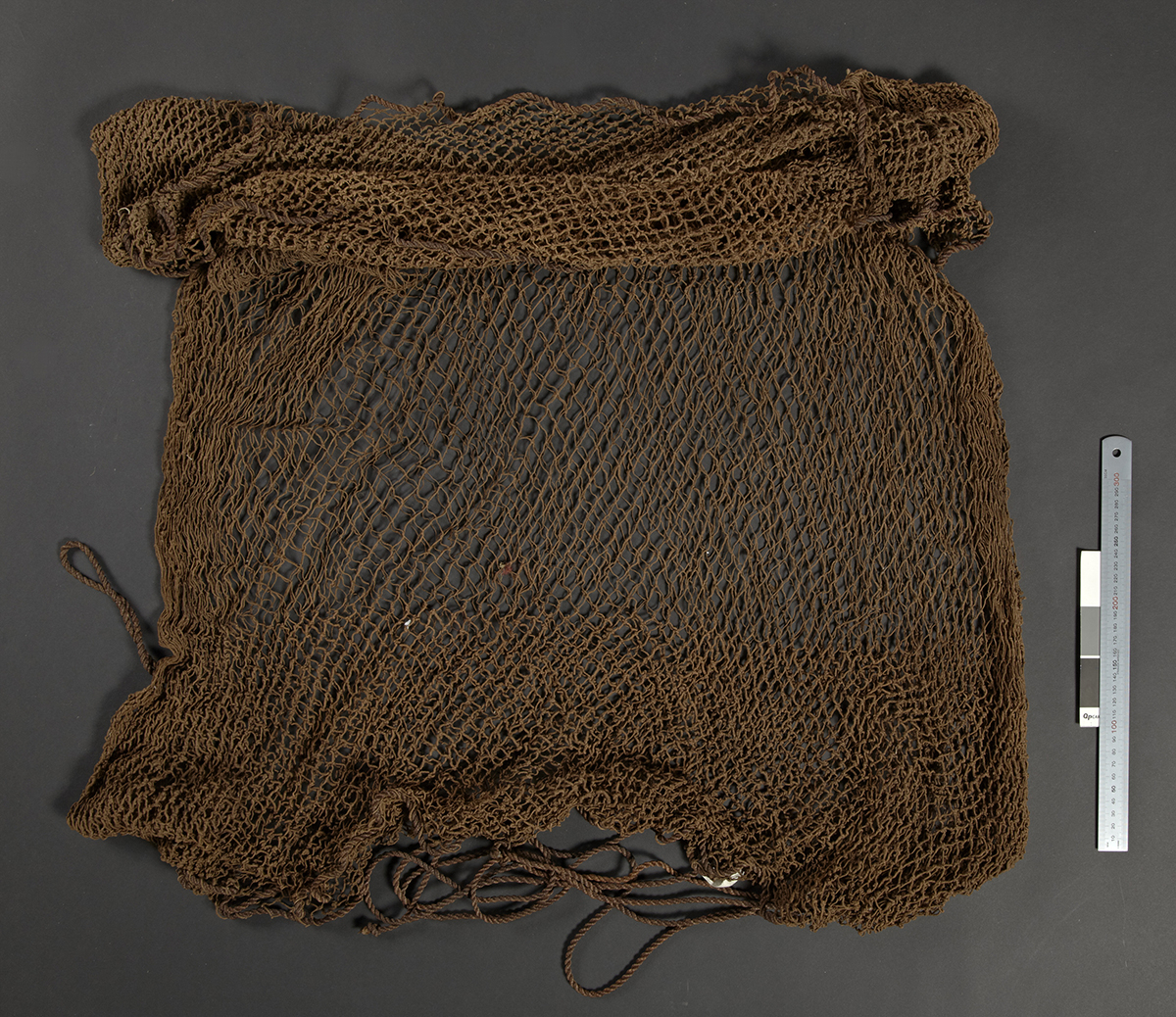 (UEM12197)&amp;#160;Rev. Bodding’s notes: 'Spread on the ground and covered by leaves. Bait is spread on top, and when the birds have gathered it is pulled and the net closes in on top. This net is used in particular when the birds come to drink water. It is then often spread in shallow water.' Material: Vegetable fibre. Length: 163 cm, width: 117 cm.