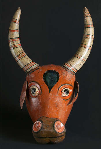 Ritual Function and Context: Kōlam theatre. UEM7006 represents a Bull. This mask is called Gonā. The mask appears in Kōlam Theatre. This mask is used in a dance called Bull and Leopard Dance ( goň-koti kōlama ). The key iconographic features of UEM7006 are: • Natural features of a real Bull. • The form and character are created by following religious art in Sinhala Buddhist Temple. The forehead of the Bull has a Bo-Tree leaf ( bō-kolayā ) symbolizing a spiritual quality of the animal. • This character comes in different skin colours such as red or brown, black and white. • Ear and horns are attached separately. Tradition: Southern Dance Tradition/Low-Country Dance Tradition. This tradition is popular in Mātara, Bentōta, Ambalaňgoda in the Southern province and Olabodūwa in Rāiygama Kōralē in Western province of Sri Lanka. Materials and Techniques: Polychrome carved wood (white, yellow, red, blue, green, black).