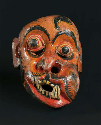 Ritual Function and Context: Kōlam theatre. UEM7010 represents the character of a soldier ( hēvāyā ). This character is used in Kōlam Theatre. In Kōlam theare, several hēvāyā masks appear as a group of soldiers. The performance is known as Hēvā-Kōlama. The key iconographic features of UEM7010 are: • The most expressive characters from Kōlam masks. • Deformed facial forms: unfocused ball eyes, marks of wounds, and swollen bumps in the face and mouth, broken teeth. • Leeches coming out of wounds. • Mask comes in deep yellow, orange or white (pale) and rarely in green skin tone. • These features make Hēvāyā character identified as Sanni mask of Sanniyäkuma ritual. • The traditional mask carvers show their creative freedom, imagination and skill in carving this character. Notes: These features have made Hēvāyā character identified as a Sanni mask from Sanniyäkuma ritual. Tradition: Southern Dance Tradition/Low-Country Dance Tradition. This tradition is popular in Mātara, Bentōta, Ambalaňgoda in the Southern province and Olabodūwa in Rāiygama Kōralē in Western province of Sri Lanka. Materials and Techniques: Polychrome carved wood (white, yellow, red, blue, green, black).