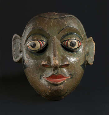 Ritual Function and Context: Kōlam theatre. UEM7022 could represent servant character of ( athawesiyā ) or policeman ( rālahami ). It is also possible this mask was applied as character of ancestor ( vaddā ) or Black man ( kāperiyā ). These characters appear in Kōlam Theatre. If the mask was used as Vaddā, it could relate to the story from Jātaka-katā performed in Kōlam Theatre. As the mask of policeman, it represents Police kōlama. The key iconographic features of UEM7022 are: • Dark skin tone suggests this character from special or lower ethnic groups, such as Vaddā or Kāperiyā. • The sideburns and tightly closed mouth painted red showing determination refer to the characters of government officials like Rālahāmî (policemen). Tradition: Kōlam Theatre/ the Southern Dance Tradition/Low-Country Dance Tradition. This tradition is popular in Mātara, Bentōta, Ambalaňgoda in the Southern province and Olabodūwa in Rāiygama Kōralē in Western province of Sri Lanka. Materials and Techniques: Polychrome carved wood (white, red, green, black).