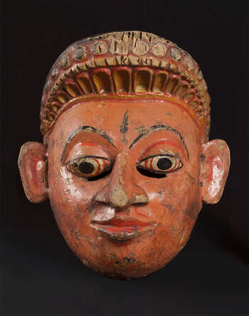 Ritual Function and Context: Kōlam theatre. UEM7026 represents a mythical character. The mask is known as Kiňdura, a male mythical character. This mask appears with its female character known as Kiňdurî in Kōlam Theatre. This mask narrates a story from Jâtaka Katha known as Saňda Kiňdurū Jâtakaya. The key iconographic features of UEM7026 are: • Short decorative headdress. • Depiction of intricate carving of palā-pethî, a Sinhālese motif ( sinhālā môsthārā ). • Orange or deep yellow based skin tone is main tone of this character. Tradition: Southern Dance Tradition/Low-Country Dance Tradition. This tradition is popular in Mātara, Bentōta, Ambalaňgoda in the Southern province and Olabodūwa in Rāiygama Kōralē in Western province of Sri Lanka. Materials and Techniques: Polychrome carved wood (white, yellow, red, black).