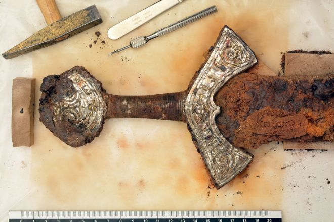 In the midst of the conservation process. The precious metal surface of the hilt is being uncovered with a hammer and micro-chisel.
