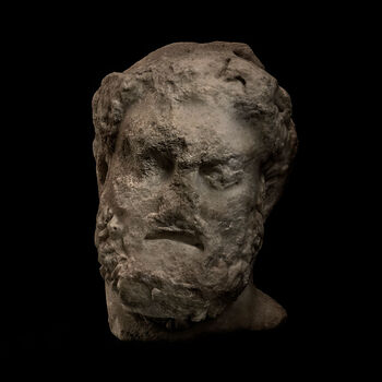 (C41753) Hode av marmor med skadet overflate fra 75–100 e.Kr., fra Askhelon (Ascalon), Israel. Det er brutt av ved halsen, men det 22 cm. høye hodet antyder at det var en del av en statue. Håret og skjegget er formet som lokker, og en krans på hodet ser ut til å ha vært formet av poppelblader, som var et av guden Hercules attributter. Hodet tilkom museet som en gjenstand i Baron Platon von Ustinows (1840–1917) samling.