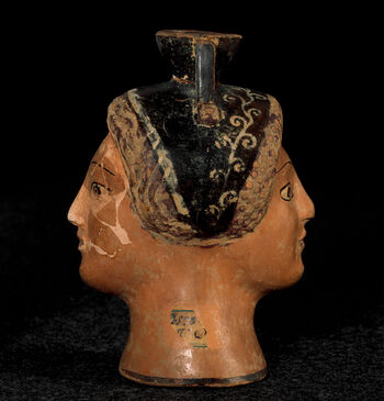 (C41784) Liten vase ( aryballos ) av keramikk fra 490 f.Kr., fra Athen eller området omkring. Den er 11,5 cm. høy, og formet som dobbelthode av en kvinne. På randen er det en innskrift, «Kytinos er vakker». Denne typen små beholdere ble gjerne brukt til velduftene oljer og salver, som var vanlig å gi i gave. Eksempelet her ble funnet av den berømte tyske arkeologen Heinrich Schliemann (1822–1890), og var blant gjenstandene som ble gitt museet i gave fra Oscar II (1829–1907) av Sverige-Norge.