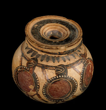 (C41804) Liten krukke ( aryballos ) av keramikk fra Korint, Hellas. Den er av en type svært tynn og blek keramikk, som var typisk da Korint var en blomstrende bystat på 500-tallet f.Kr., da den ble laget. Slike krukker ble brukt til velduftende salver og oljer, og de er gjerne bemalte. Dette eksempelet, som viser tre krigere med runde skjold, ble funnet av den berømte tyske arkeologen Heinrich Schliemann (1822–1890), og var blant gjenstandene som ble gitt museet i gave fra Oscar II (1829–1907) av Sverige-Norge.