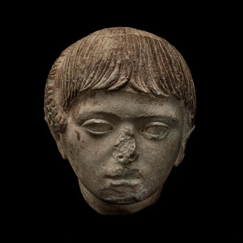 (C42184) Hode av marmor med skinnende krystaller fra Samaria Sebaste, Palestina. Det er ca. 20 cm. høyt, brutt av ved halsen, og er sannsynligvis fra en gravstatue. Det er stilistisk datert til 120–130 e.Kr. Den kortklippede frisyren viser at portrettet er av en gutt, og en dobbeltflette av hår som har fått vokse langt er trukket skrått oppover, og festet på issen. Fletten kan symbolisere at han var viet til den den egyptiske gudinnen Isis. Portrettet tilkom museet som en gjenstand i Baron Platon von Ustinows (1840–1917) samling.