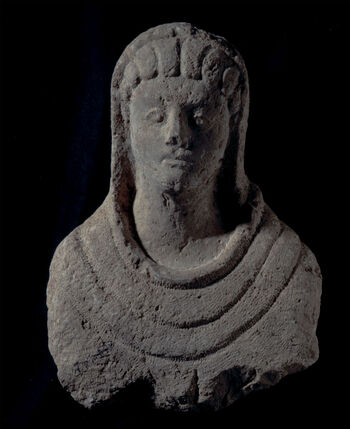 (C42233) Gravbyste av en kvinne, 54 cm høyt, av en type som var vanlig i Decapolis-byene fra det 2. til det 4. århundre e.Kr. Eksempelet her er fra Skythopolis (Beit-She’an), Israel, som var en av de ledene byene i Decapolis, og hører til i en gruppe som kjennetegnes av at de har haker med kløft. De såkalte «Decapolis-gravbystene» er påvirket av romersk portrettkunst, som var en naturlig følge av gresk-romersk påvirkning på området. Dette portrettet har store øyne, med markert iris og pupiller, og håret legger seg i bølger på hver side av en midtskill. Hodet hennes er dekket av et sjal eller en kappe. Eksempelet her tilkom museet som en gjenstand i Baron Platon von Ustinows (1840–1917) samling.