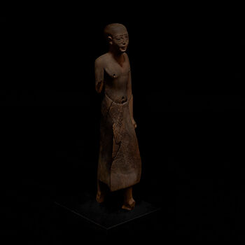 (C47677) Trefigur av stående mann på 43 cm. av en type som ble laget mellom 2345 og 2025 f.Kr. Den viser en mann kun iført en lang kilt med trekantet front, som sammen med posituren kan antyde at han representerer en prest eller en embetsmann i et egyptisk tempel. I venstre hånd holder han en sylinderformet gjenstand, som kan være et segl. Figuren ble anskaffet i Egypt mellom 1967 og 1870 via Jens Lieblein (1827–1911), Norges første egyptolog.