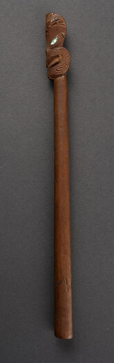 (UEM180)&amp;#160; Gudefigur i tre også kjent som Tiki wananga fra Hokianga, Aotearoa New Zealand. Øynene er laget av perlemor. Datert til den klassiske maoriperioden (Te Puawaitanga 1500–1800). En Tiki wananga er vanligvis identifisert som en representasjon av forskjellige guder som for eksempel Tangaroa, Tane, Rongo, Haumia. Måten skaftet er behandlet på, fungerer som representasjon av de forskjellige gudenes attributter. Skaftet på denne gjenstanden hadde muligens flettede tau festet rundt og røde fjær festet rett under hodet. Tiki wananga anses for å være svært sjeldne gjenstander. Mesteparten av dem ble ødelagt av misjonærer på 1800-tallet. Gjenstanden ble innsamlet av Fredrik Ring da han var handelsmann i Valparaiso i Chile på 1820-tallet. Konsul Ring donerte gjenstanden til Etnografisk museum i 1833.&amp;#160;&amp;#160; Materiale: Perlemor, skjell, tre &amp;#160; Region og kultur: New Zealand – Māori