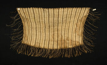 (UEM182)&amp;#160; Maori skulder- eller hoftekappe (kakahu). Kan muligens dateres til den postklassiske maoriperioden (Te Huringa 1800 – i dag). Kappen kommer fra Hokianga, Aotearoa New Zealand. Kappen ble vevd av New Zealandsk linfiber (Harakeke), og tilhører trolig typen kaitaka, som ansees å være et av de mest ærverdige av de tradisjonelle maori-plaggene. Disse kappene ble gitt, og blir fortsatt gitt, som prestisjefylte gaver for å befeste viktige relasjoner og hendelser knyttet til familie og andre individer. Det relativt enkle loddrette vevde mønsteret, taniko, tilsier at kappen kan dateres til tidlig 1800-tallet Mønsteret taniko kan muligens symbolisere forskjellige fortellinger hvor tolkningen avhenger av region og stammetilhørighet (iwi).&amp;#160; Materiale: Ben, ukjent fiber Region og kultur: New Zealand – Maori&amp;#160;