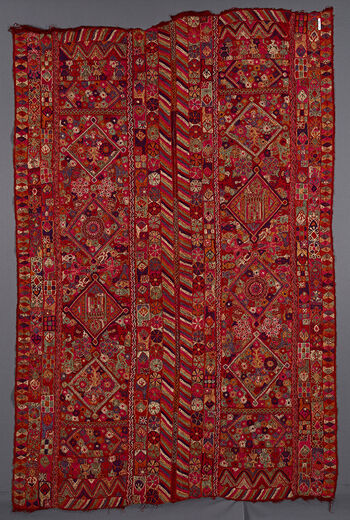 UEM49193. De innerste loddrette kantene av teppets to paneler består av karakteristisk flerfarget mønster i form av diagonale linjer.  På de ytre kantene er det diamantformet mønster. Motiver: store diamanter, blomster, jenter i en rekke. Muligens fire blonde havfruer, kamelryttere, kransede figurer, vaser og muligens to mihrab/moskéer på hvert panel. 