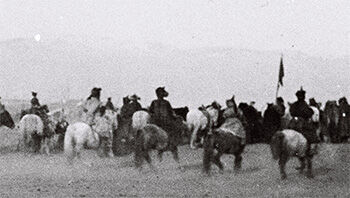Historical black and white photo of a group of people and horses